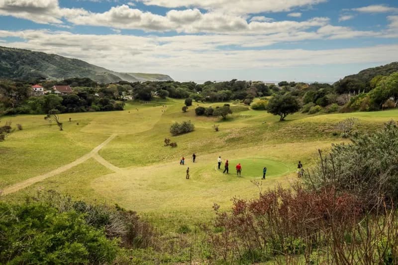 Players on an open fairway with the forested hills behind